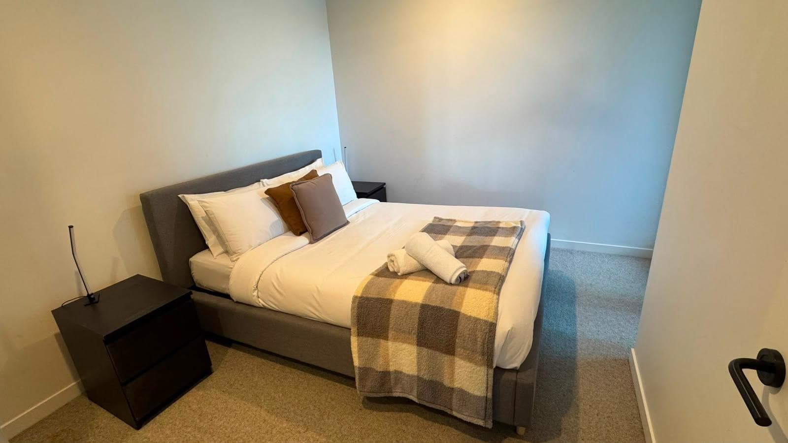 Freshly made Airbnb bedroom with styled throw and towels in Brisbane
